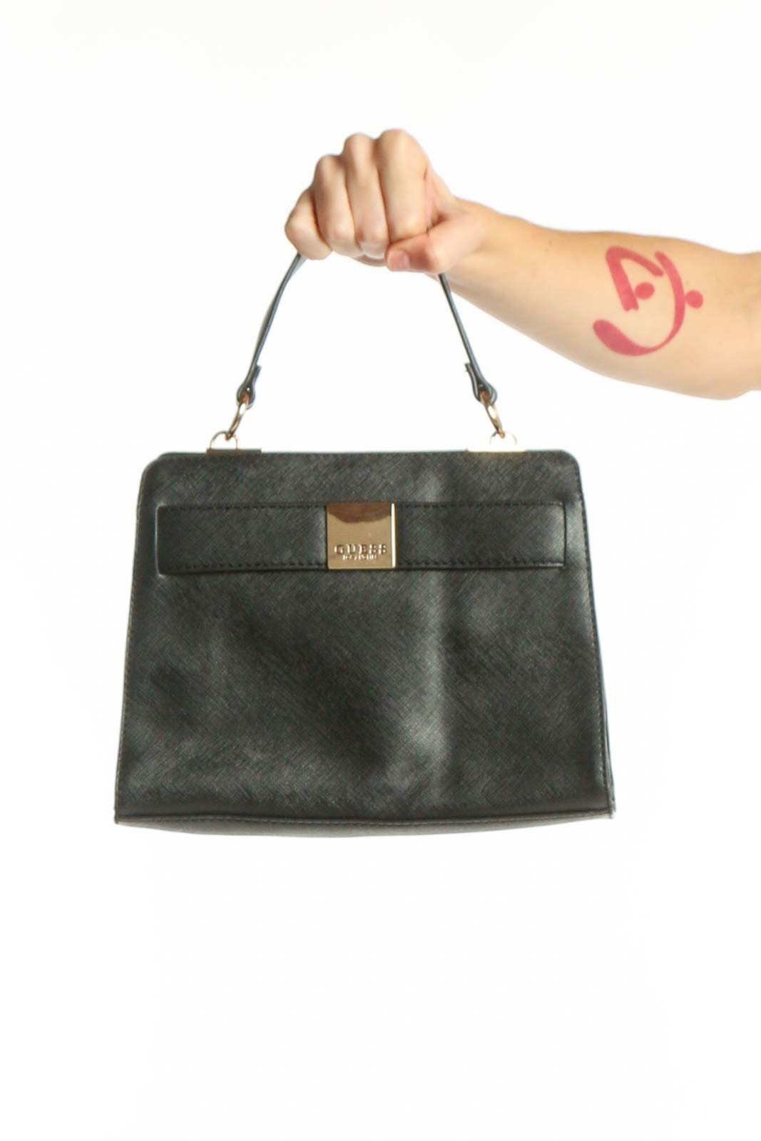Black Guess crossbody bag with gold-tone metal clasp and dual handles, shown being held