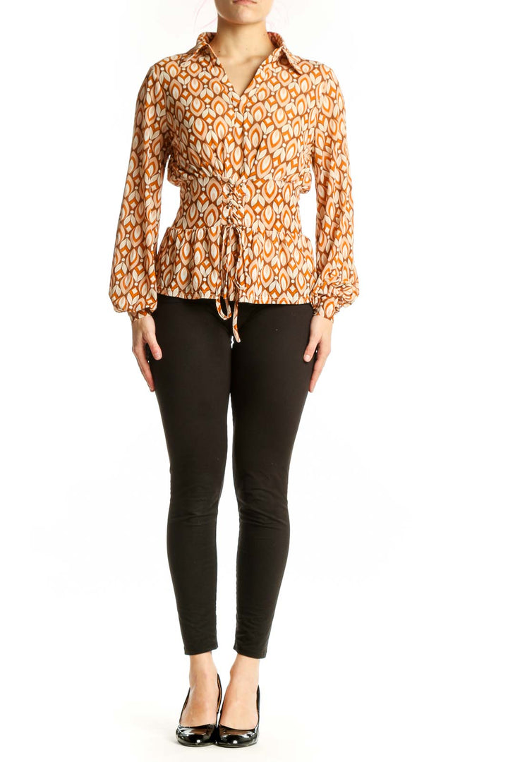 Orange geometric print wrap blouse with balloon sleeves and tie-front closure, worn with black trousers