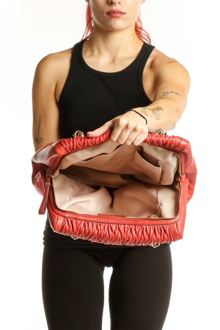 Back view of red quilted Coach shoulder bag worn on model's shoulder, showing structured silhouette and quilted texture