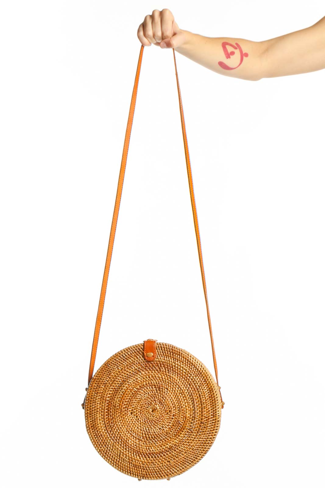 SilkRoll tan woven round shoulder bag with tan leather straps held by hand