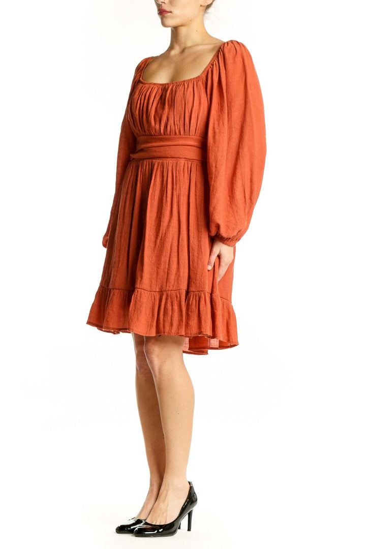 Front view of orange puff sleeve empire waist dress with gathered neckline and tiered ruffle hem