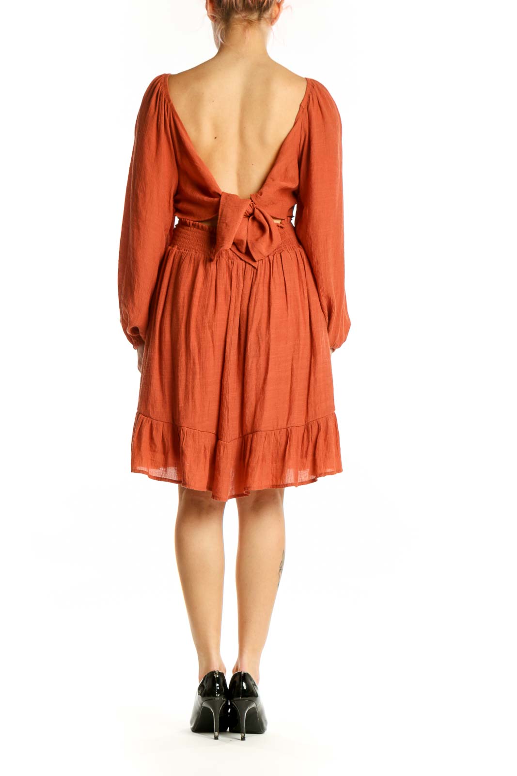 Back view of orange puff sleeve empire waist dress showing gathered back and tiered ruffle detail