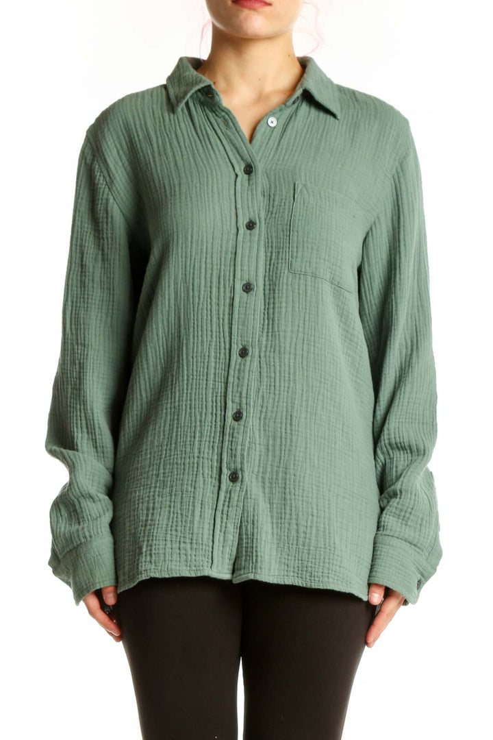 Sage green cotton button-up shirt with collar and chest pocket, front view on model