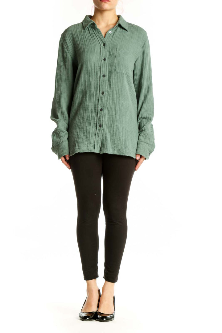Sage green cotton button-up shirt with collar and chest pocket, front view on model