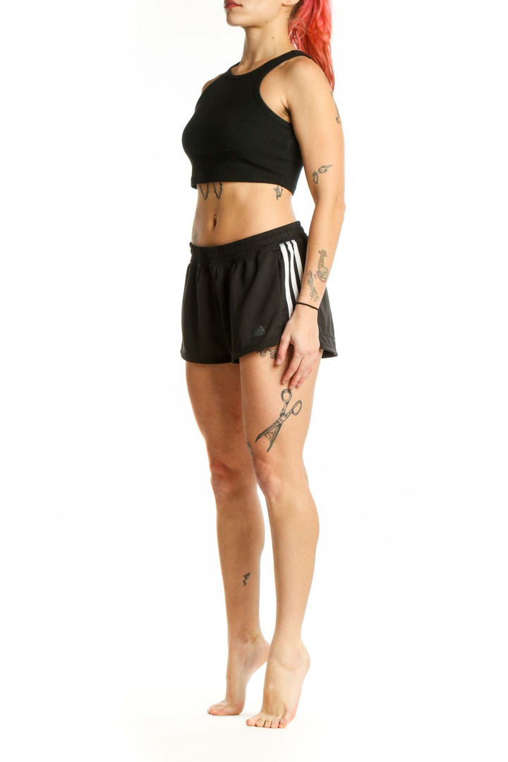 Black Adidas athletic shorts with three-stripe detailing, front view on model