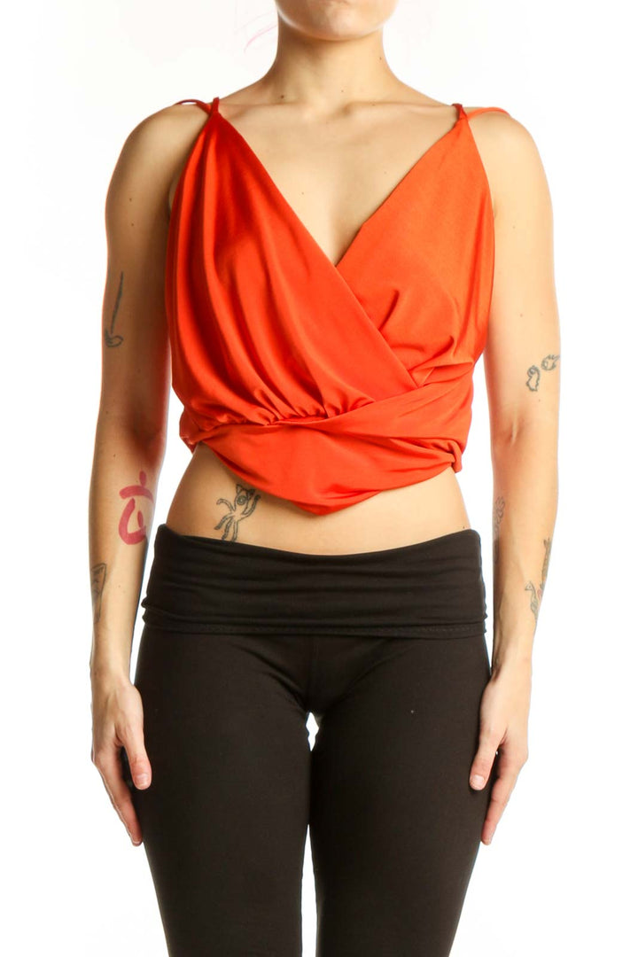 Red wrap crop top with side tie detail and sleeveless design, worn with black pants