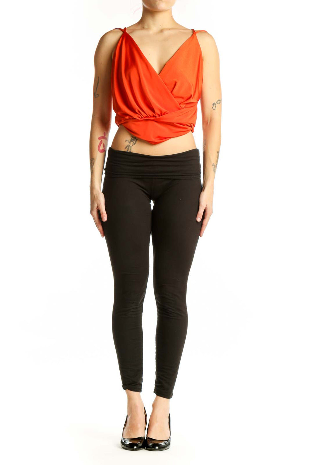 Red wrap crop top with side tie detail and sleeveless design, worn with black pants
