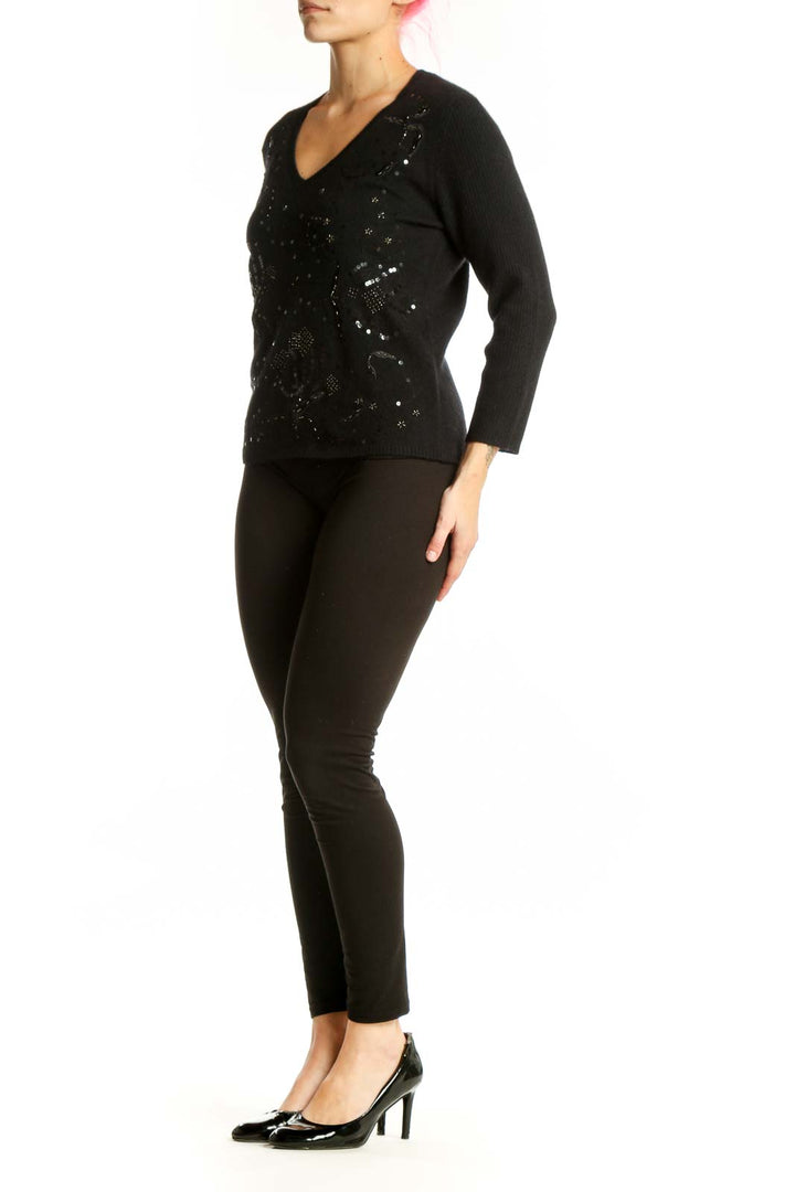 Black embellished merino wool pullover with beadwork and sequin detail, V-neckline, long sleeves, worn with black pants