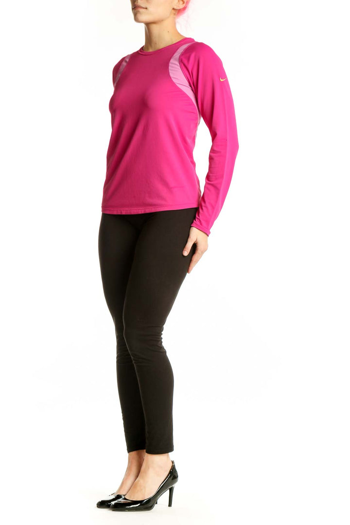Front view of pink Nike long sleeve athletic top with mesh shoulder panels on model, paired with black leggings