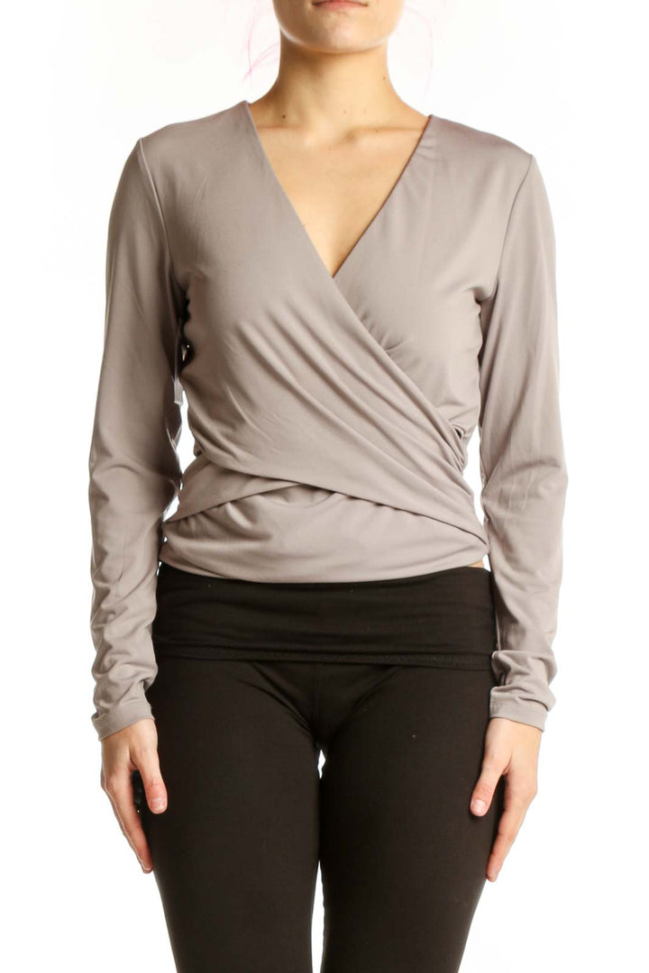 Beige wrap long sleeve top with flattering wrap-front design and fitted waist, paired with black leggings