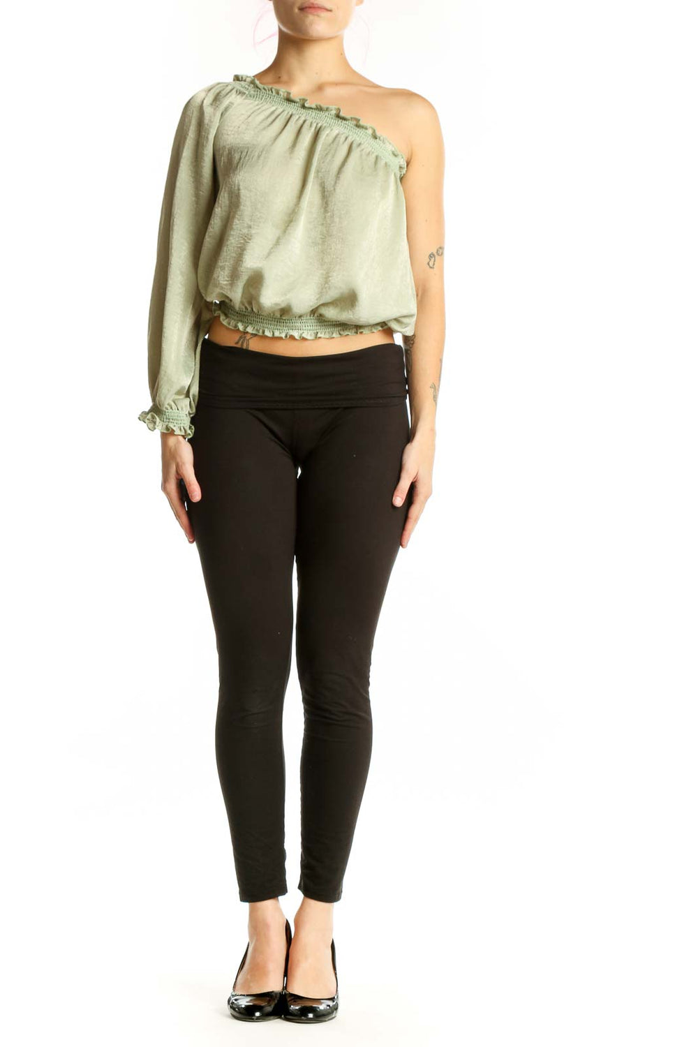 Sage green one-shoulder crop top with long sleeves and ruched waistband, paired with black pants