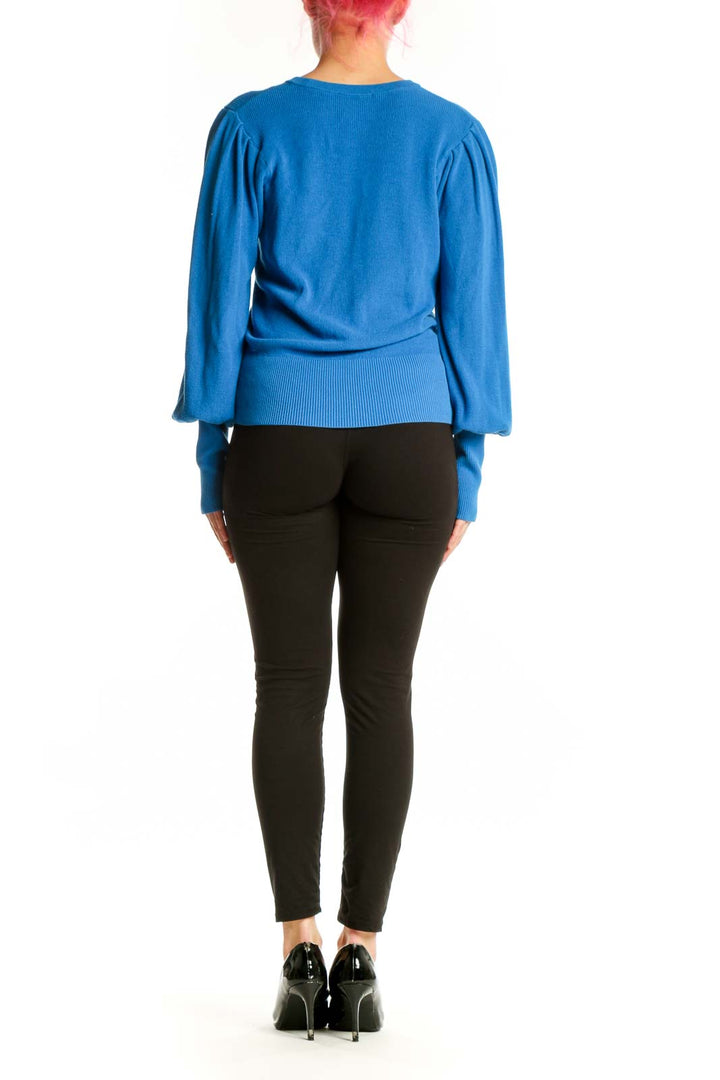 Back view of blue puff sleeve knit pullover showing relaxed fit and voluminous sleeves