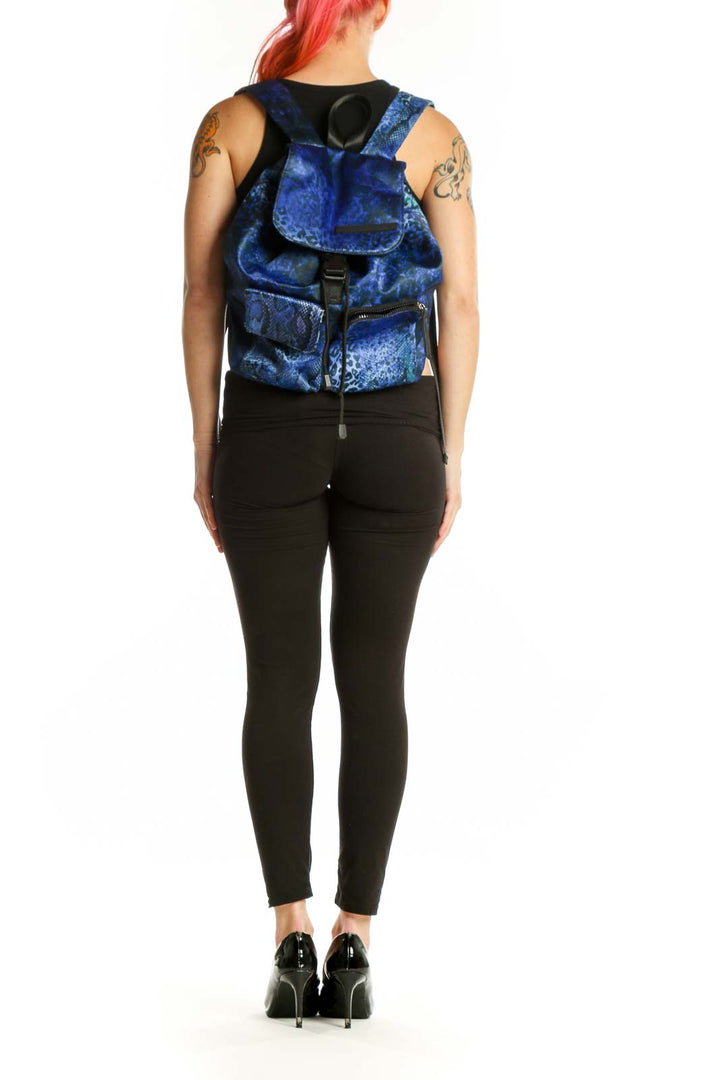Blue velvet backpack with snake print design and black straps held by hand