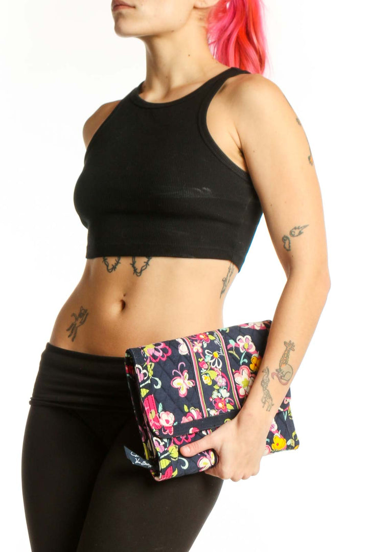 Black quilted Vera Bradley clutch with pink, yellow, and white floral pattern held in hand