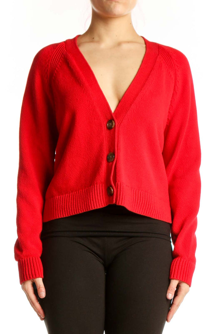 Red cropped cardigan with button-front closure and V-neckline, styled with black pants