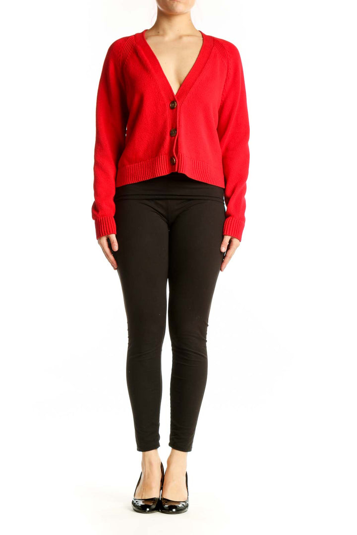 Red cropped cardigan with button-front closure and V-neckline, styled with black pants