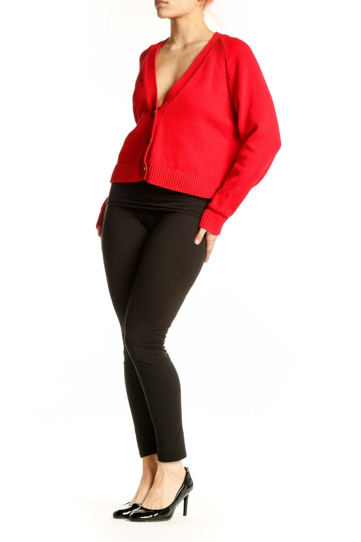 Red cropped cardigan with button-front closure and V-neckline, styled with black pants