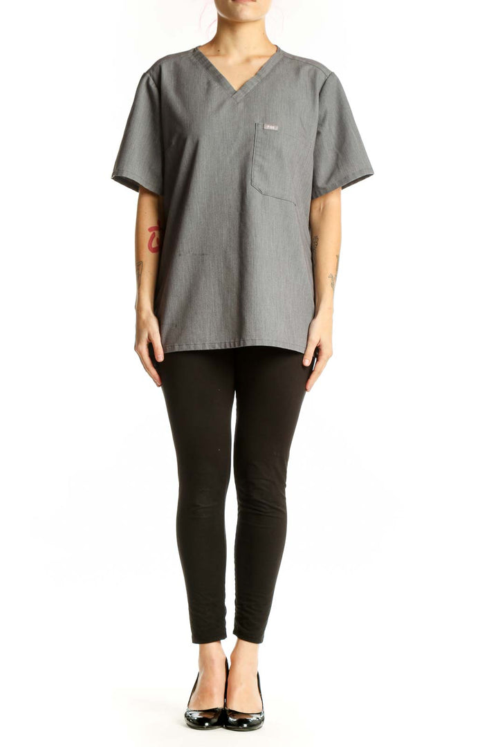 Gray V-neck FIGS medical scrub top with chest pocket, front view on model