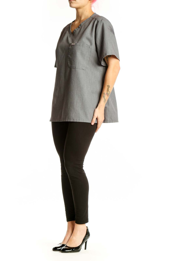 Gray V-neck FIGS medical scrub top with chest pocket, front view on model