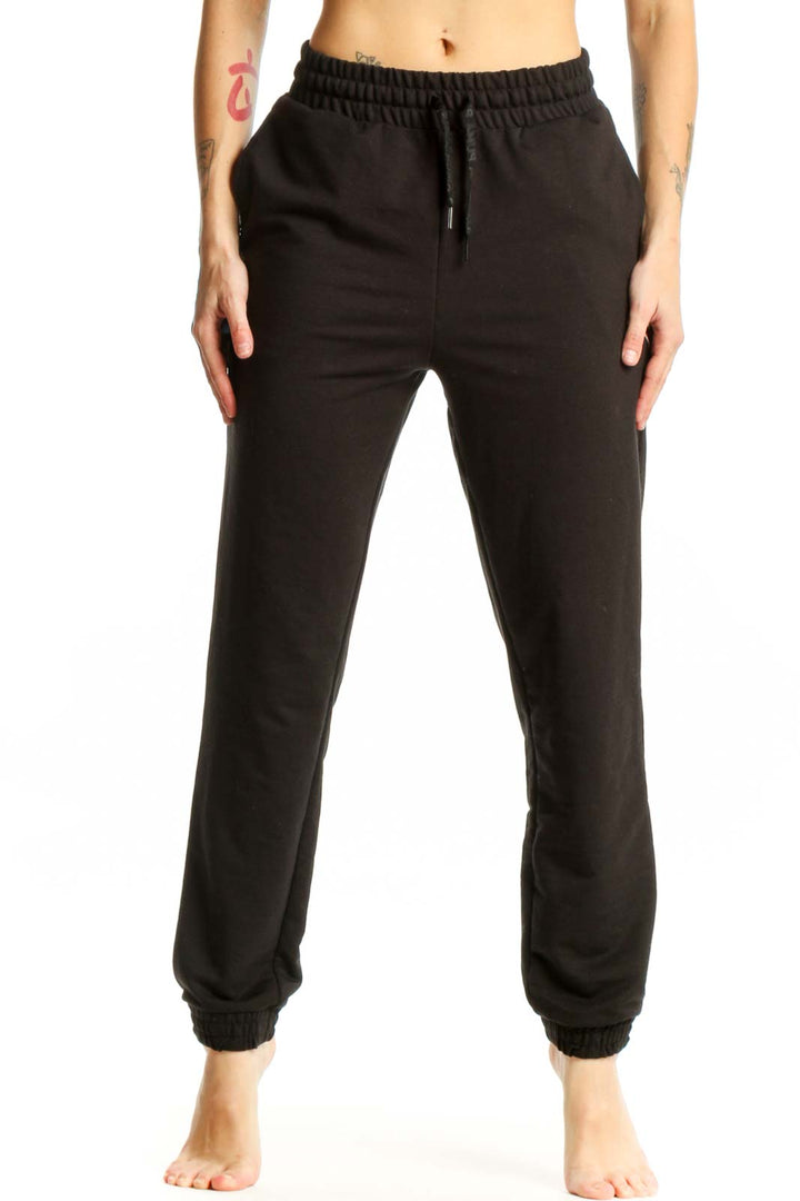 Black Puma jogger sweatpants with drawstring waistband and tapered ankles, front view on model