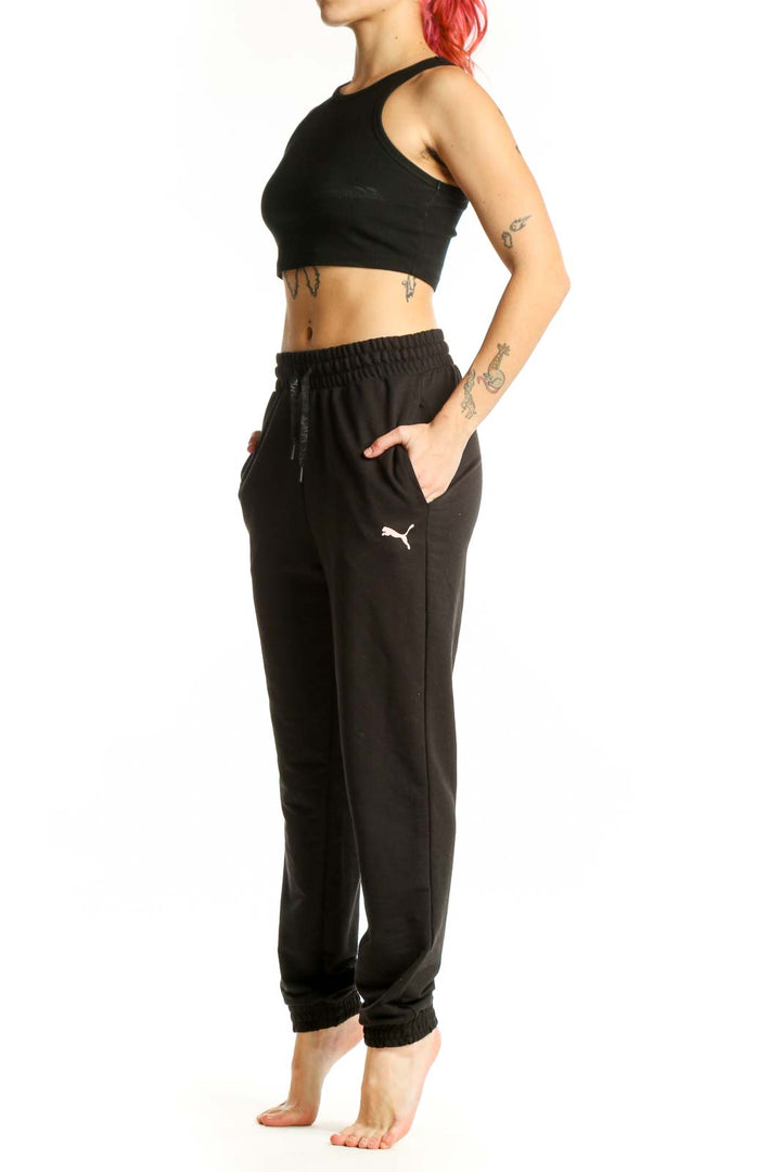 Black Puma jogger sweatpants with drawstring waistband and tapered ankles, front view on model