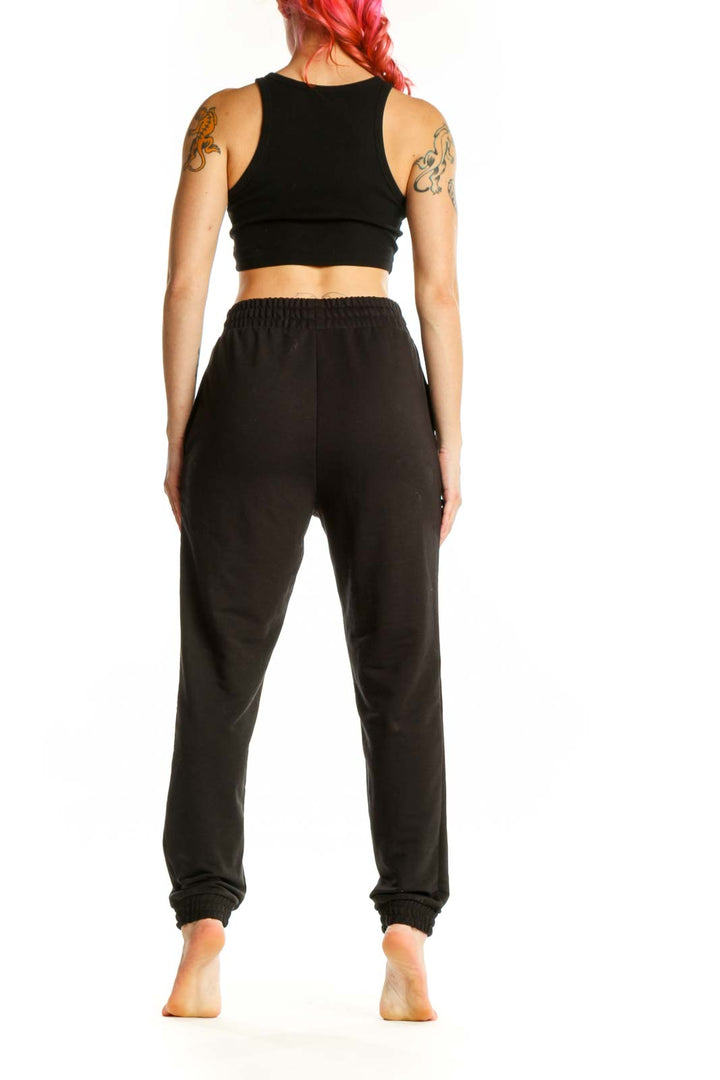 Black Puma jogger sweatpants with side pockets and Puma logo, back view on model