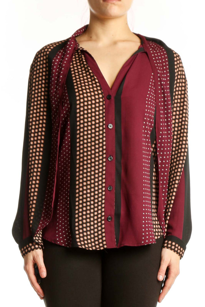 Burgundy polka dot button-up blouse with cream and gold patterned sleeves, front view on model