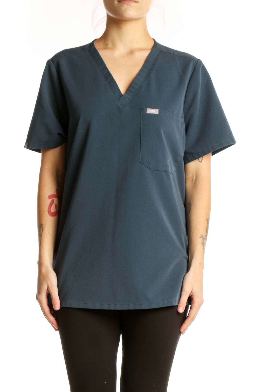 Navy V-neck FIGS medical scrub top with chest pocket, front view on model