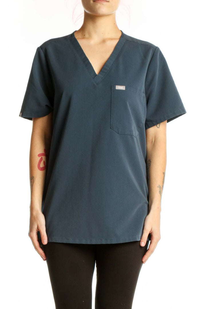 Navy V-neck FIGS medical scrub top with chest pocket, front view on model