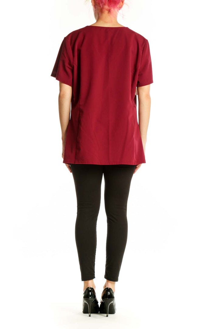 Burgundy v-neck short sleeve top with side pockets, back view on model wearing black pants