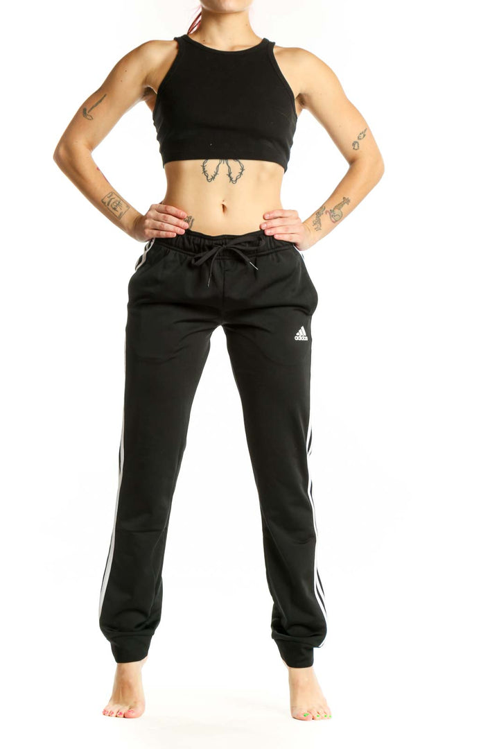 Black Adidas striped jogger pants with white three-stripe detail, drawstring waistband, and tapered ankles, front view