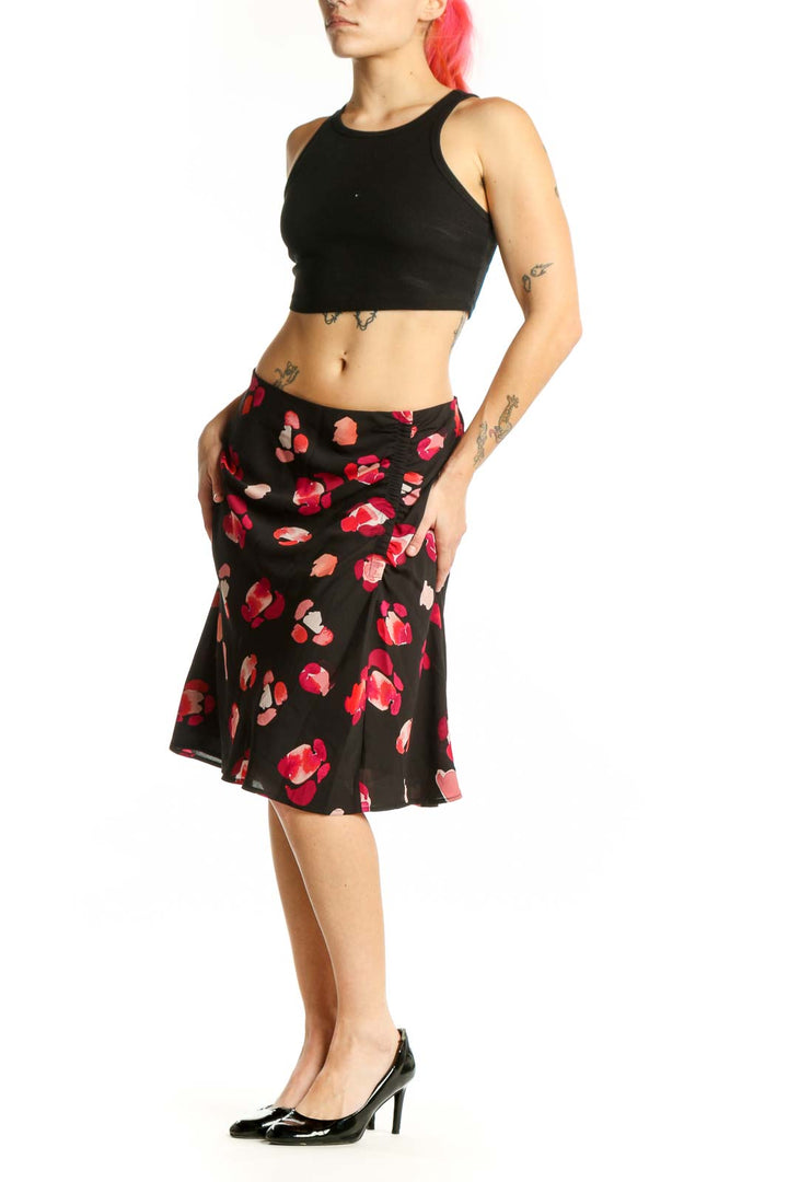Black knee-length skirt with red and pink floral print, front view on model