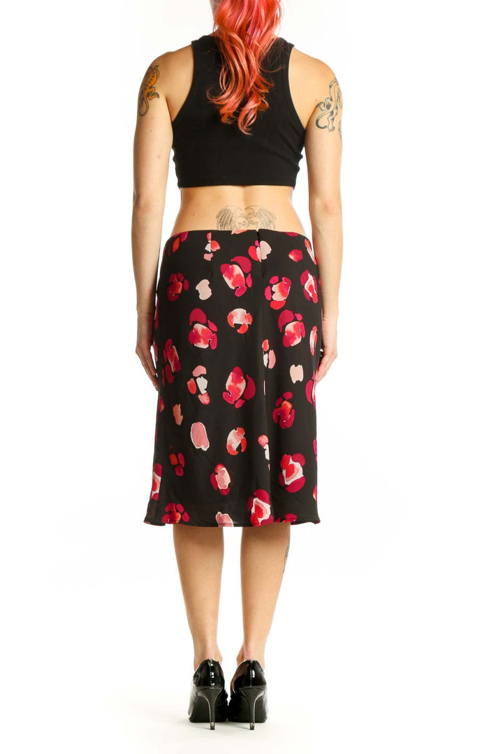 Black knee-length skirt with red and pink floral print, back view on model