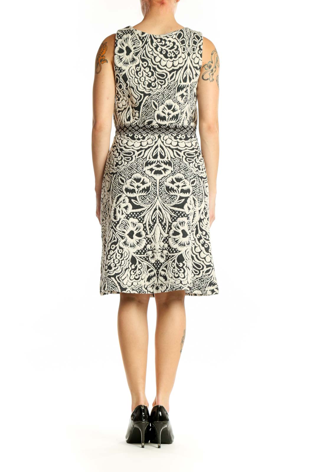 Back view of cream and black ornamental print sleeveless dress showing fitted bodice and flowing skirt