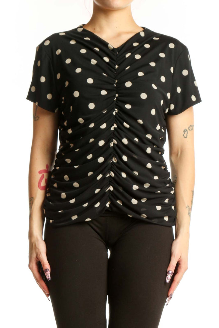 Black polka dot ruched short sleeve top with V-neckline, front view on model