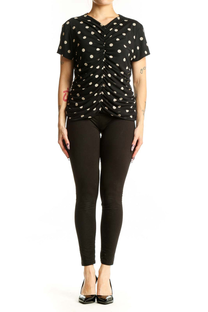 Black polka dot ruched short sleeve top with V-neckline, front view on model