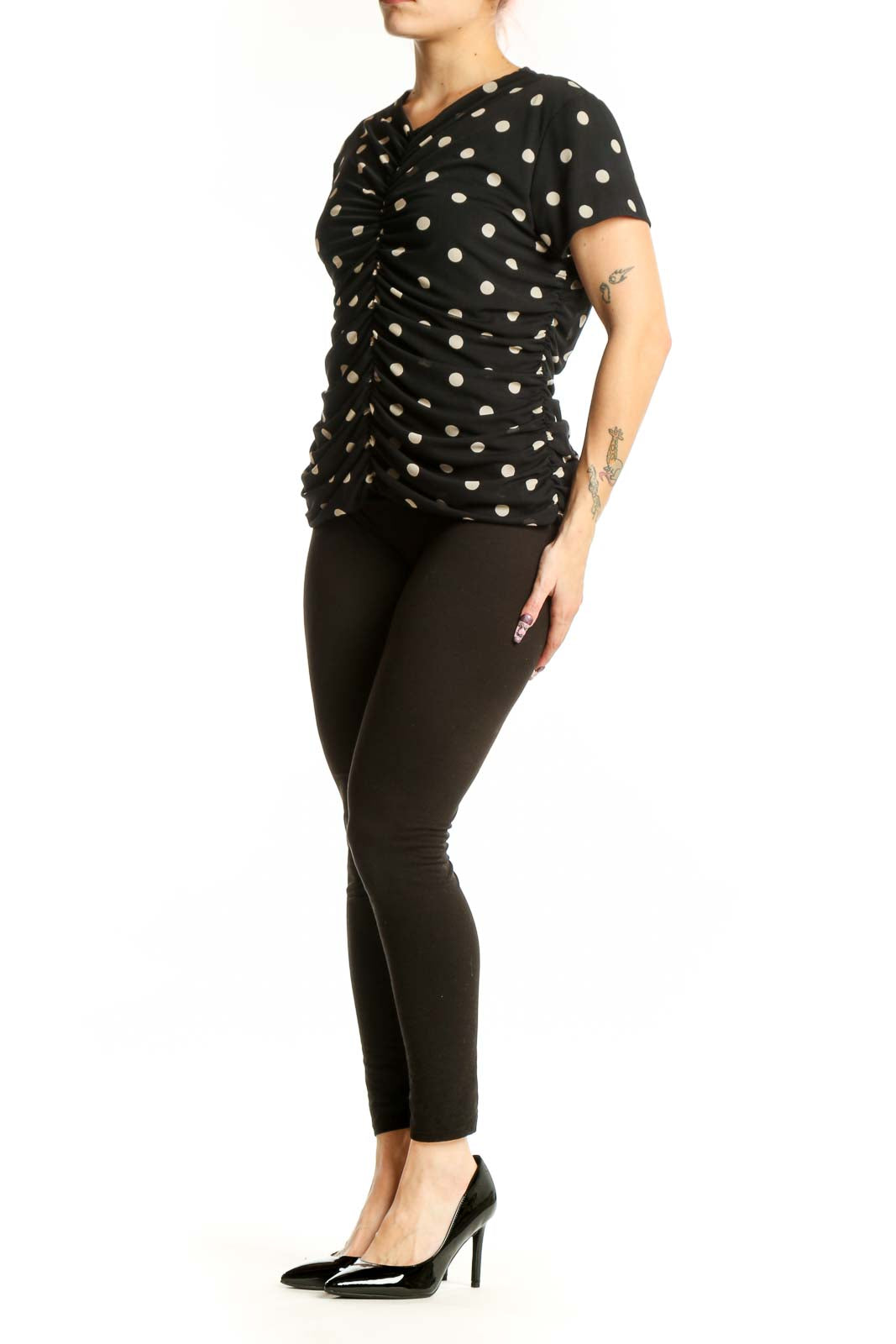 Black polka dot ruched short sleeve top with V-neckline, front view on model