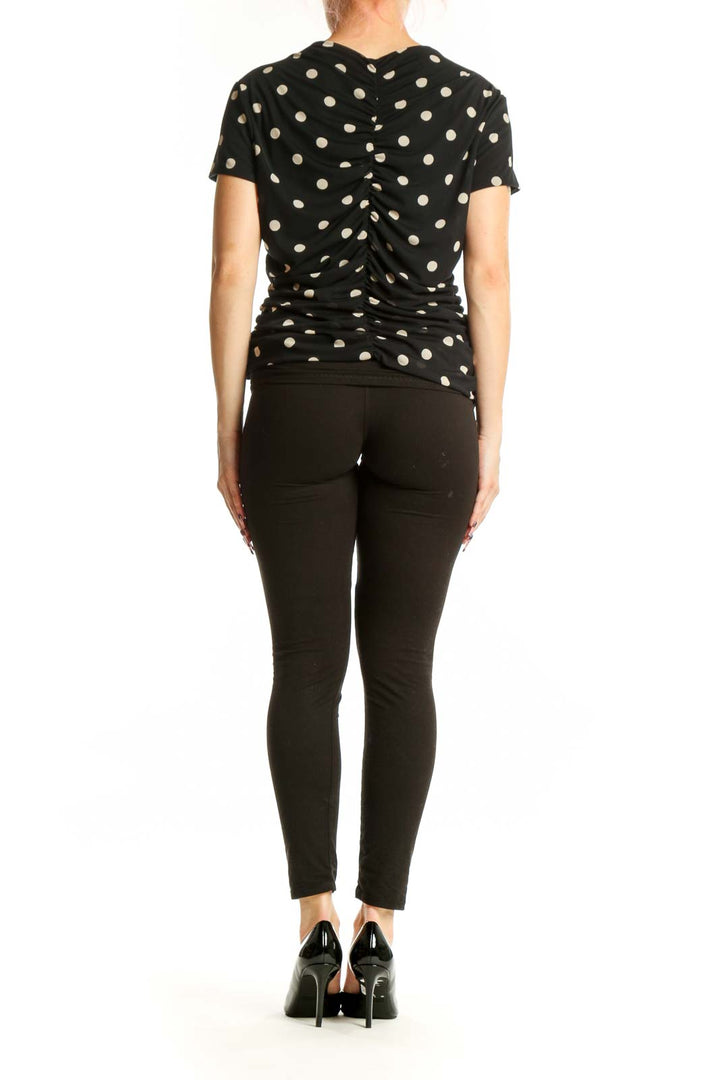 Black polka dot ruched short sleeve top, back view showing ruched design and fit