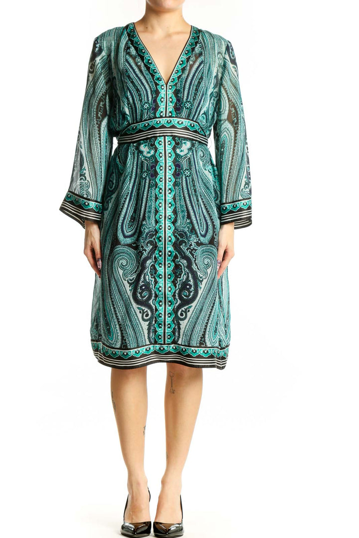 Front view of teal paisley print wrap dress with long sleeves and decorative trim detailing