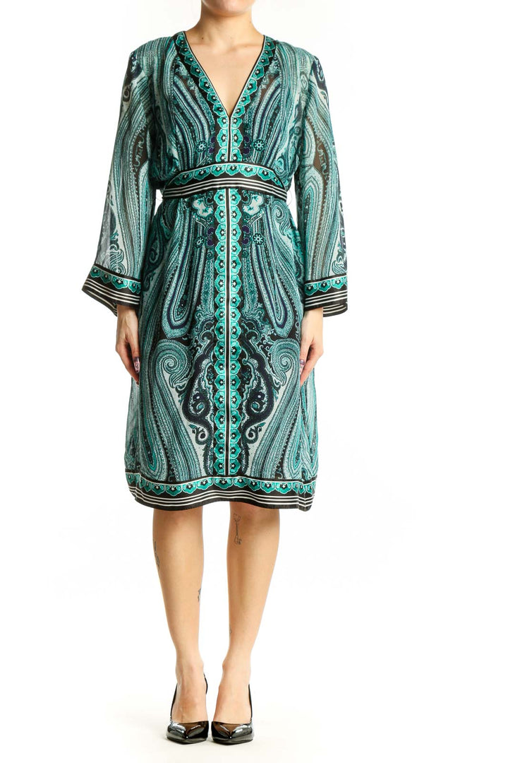 Front view of teal paisley print wrap dress with long sleeves and decorative trim detailing