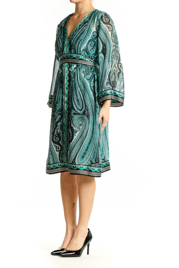 Front view of teal paisley print wrap dress with long sleeves and decorative trim detailing