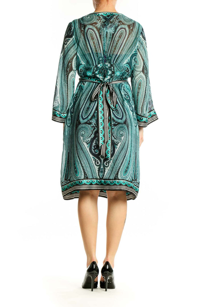 Back view of teal paisley print wrap dress showing cinched waist and button detail