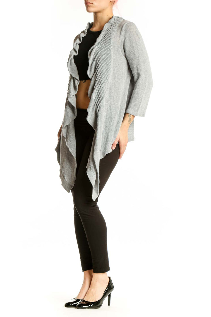 Gray cotton cardigan with ruffled front detailing and open front design, worn over black top