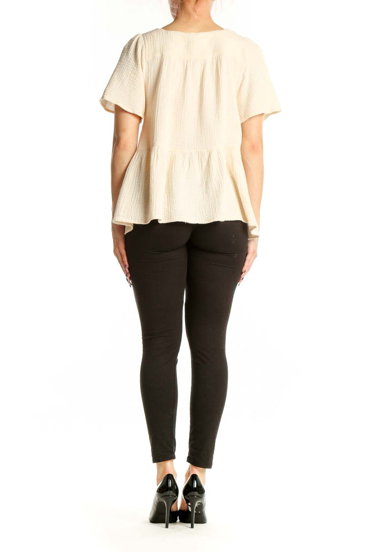 Back view of cream cotton embroidered top showing gathered waist and short sleeve design