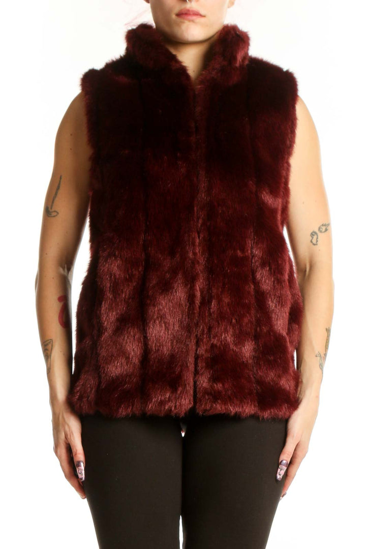 Burgundy faux fur sleeveless vest with front zip closure, worn as a layering piece over black pants