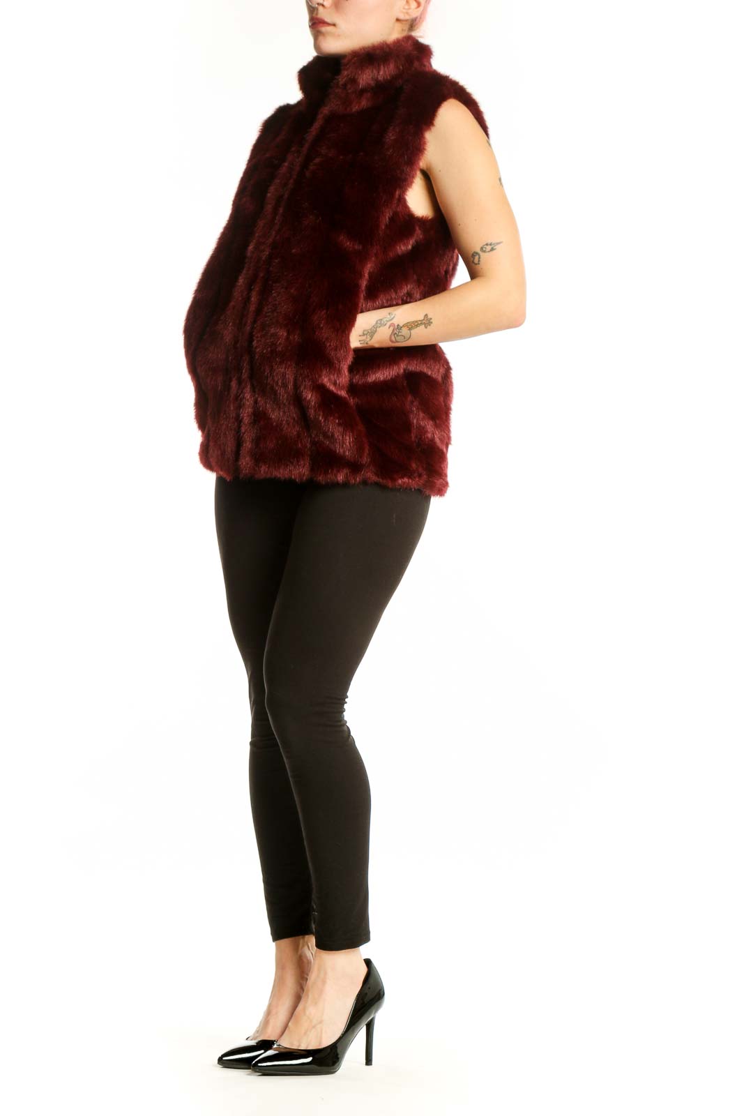Burgundy faux fur sleeveless vest with front zip closure, worn as a layering piece over black pants