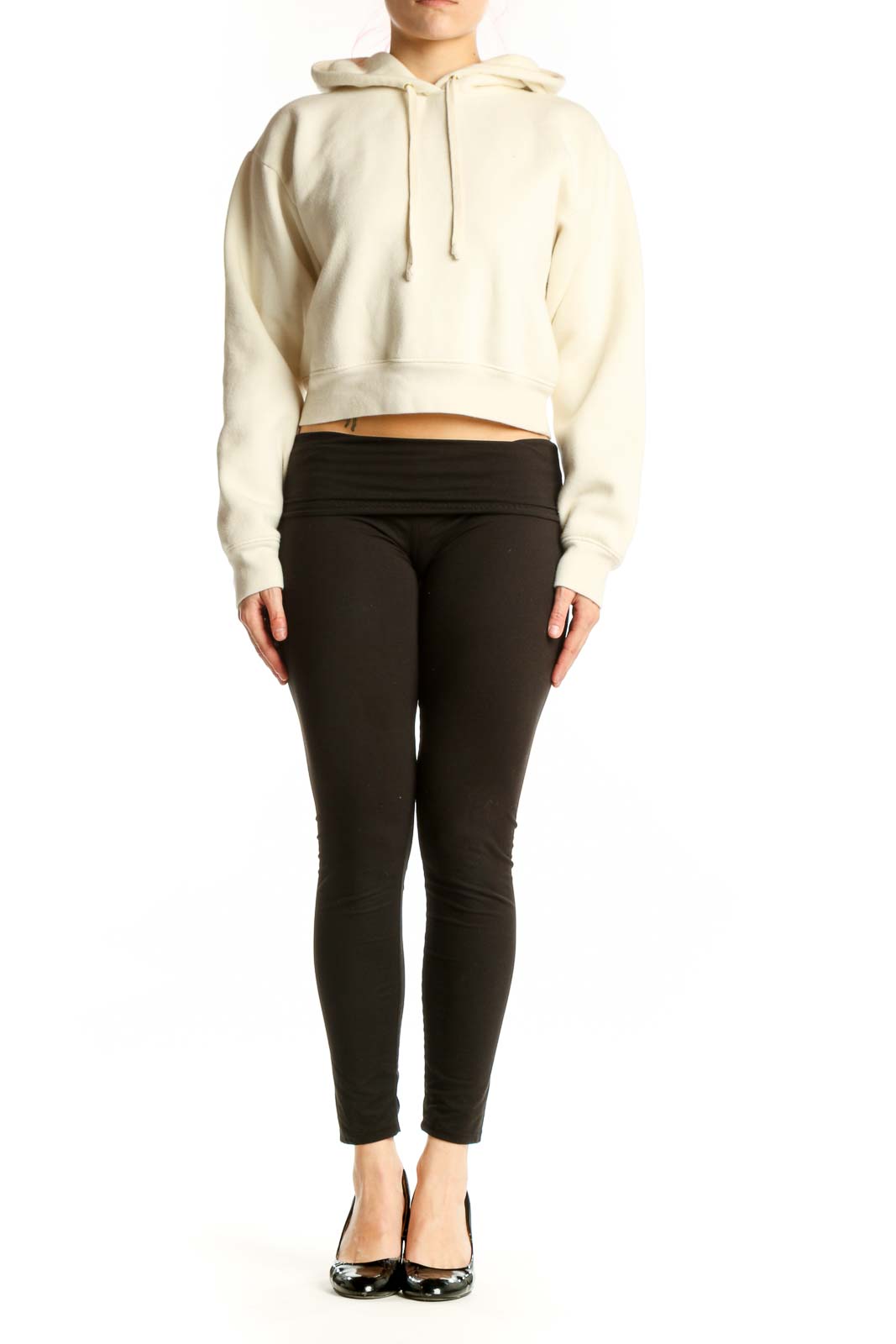 Front view of cream cropped hoodie with drawstring hood and long sleeves on model wearing black pants