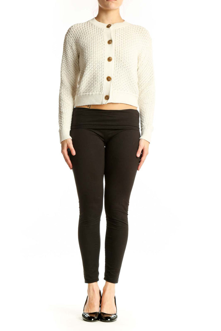 Cream textured knit cardigan with wood-tone button front and cropped silhouette, worn with black pants
