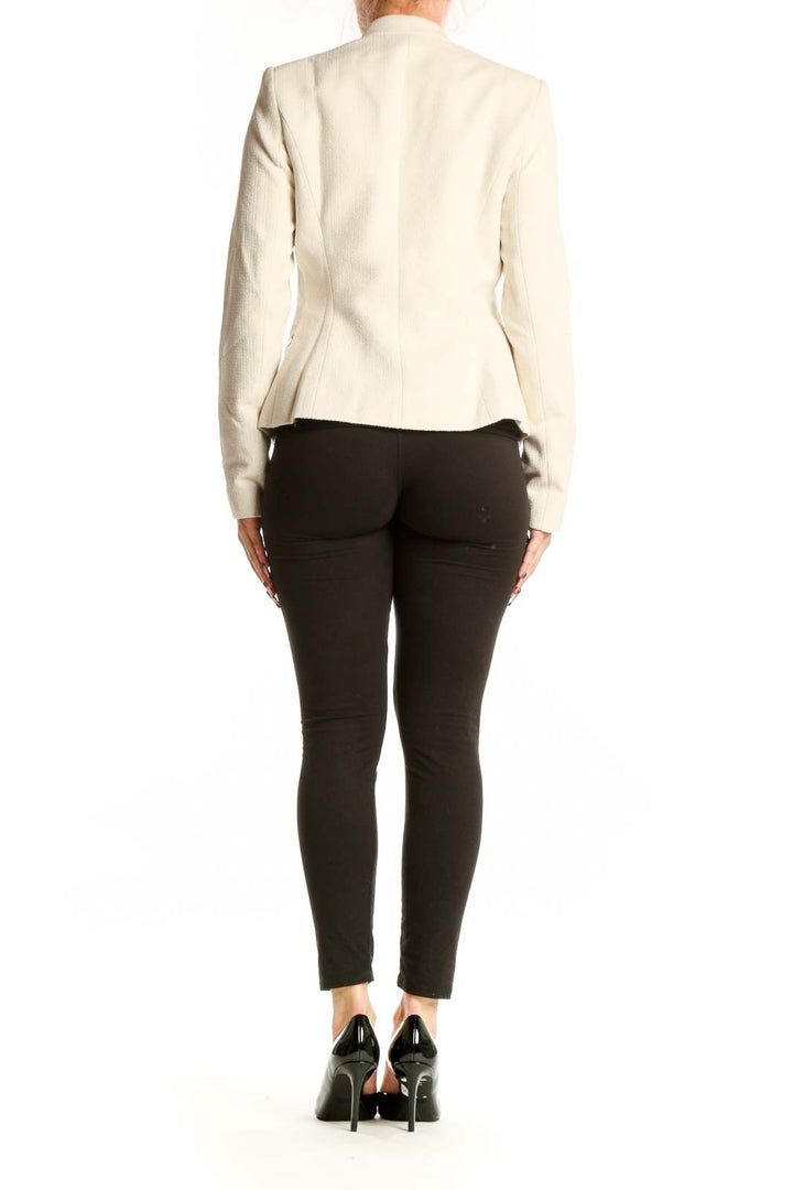 Back view of cream polyester blazer by Calvin Klein, XS size, showing structured shoulders and cropped length