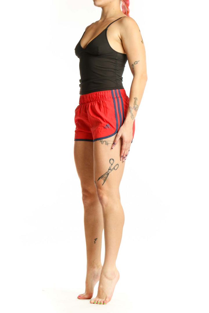 Red Adidas athletic shorts with navy trim, front view on model, XS size